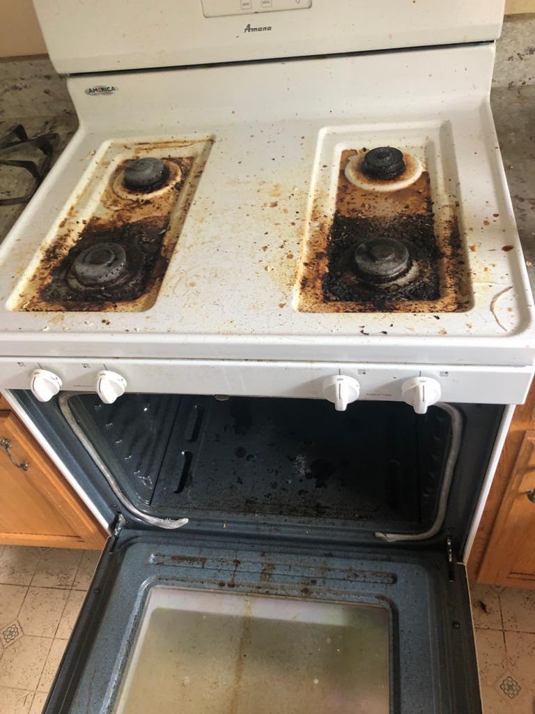 Gas stovetop and oven covered in burnt-on grease before cleaning