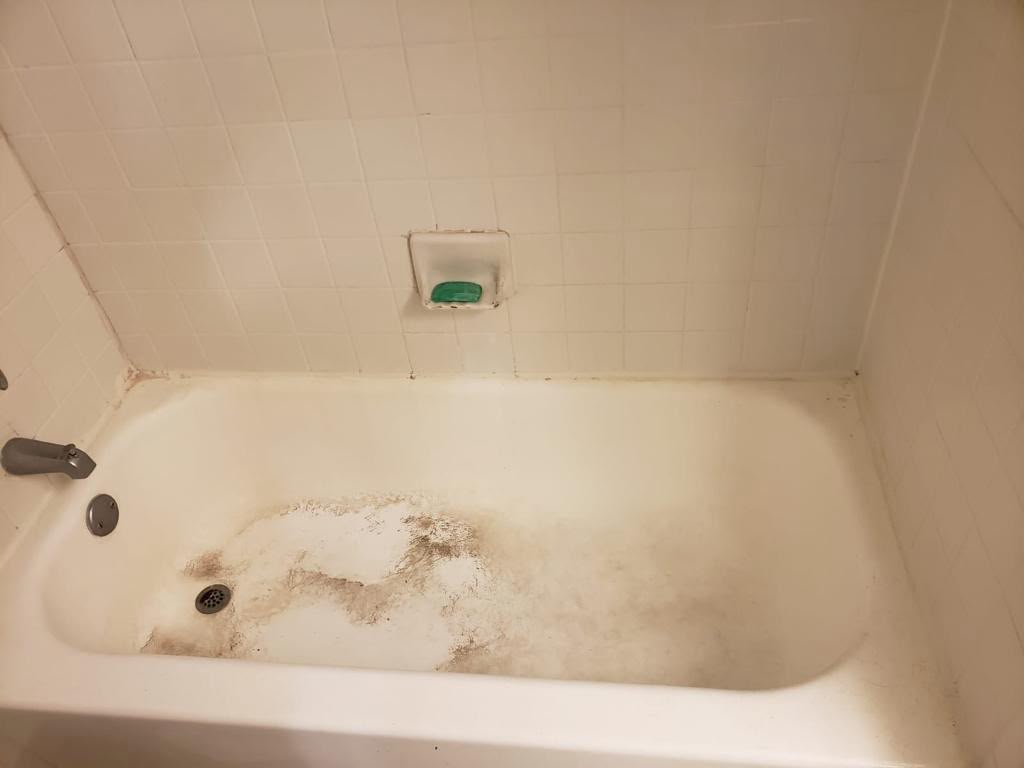 Bathtub with heavy dirt buildup and stains before a deep cleaning